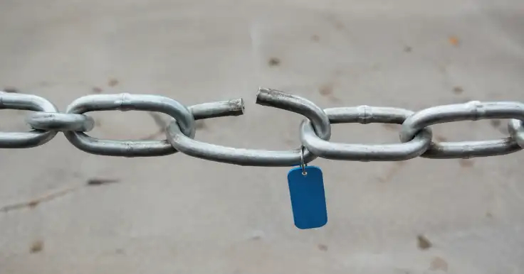 Cadena metálica con un eslabón partido y una etiqueta azul colgante.