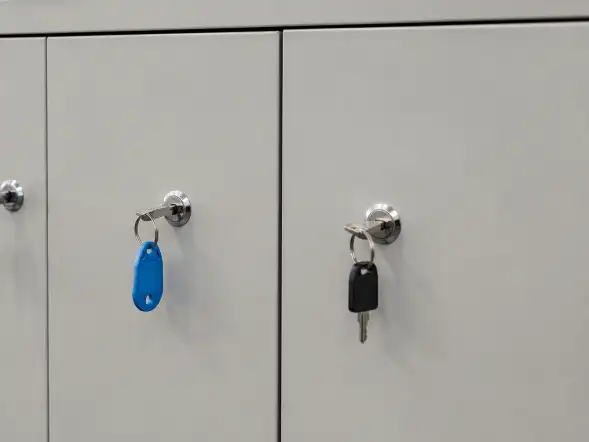 Tres llaves insertadas en las cerraduras de un armario; dos llevan etiquetas azul y negra.