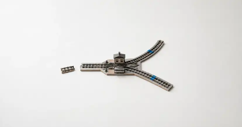 Maqueta ferroviaria con una estación, tres vías divergentes y un tramo de riel desconectado.