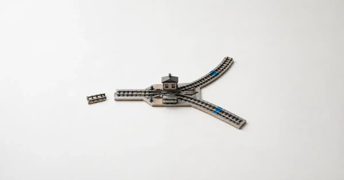 Maqueta ferroviaria con una estación, tres vías divergentes y un tramo de riel desconectado.