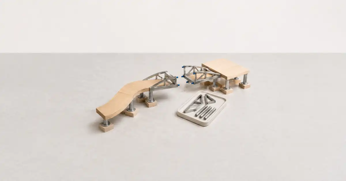 Maqueta de una rampa y un puente de madera desmontado sobre fondo blanco.