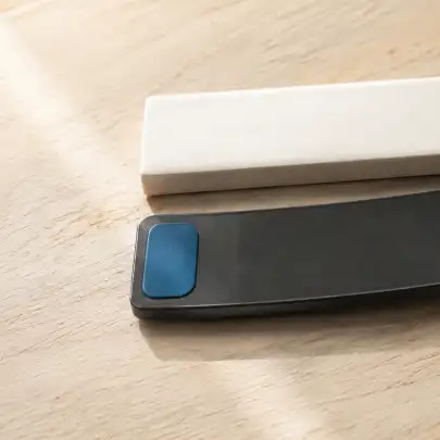 Dos barras rectangulares, una blanca y otra negra con un extremo azul, sobre una mesa de madera.