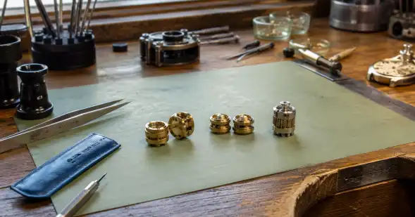 Pequeñas piezas cilíndricas de un mecanismo están desmontadas y ordenadas junto a herramientas de precisión.