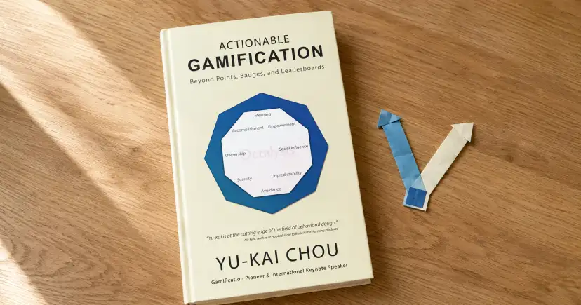 Portada de Actionable Gamification sobre una mesa de madera, junto a una ficha azul de juego.