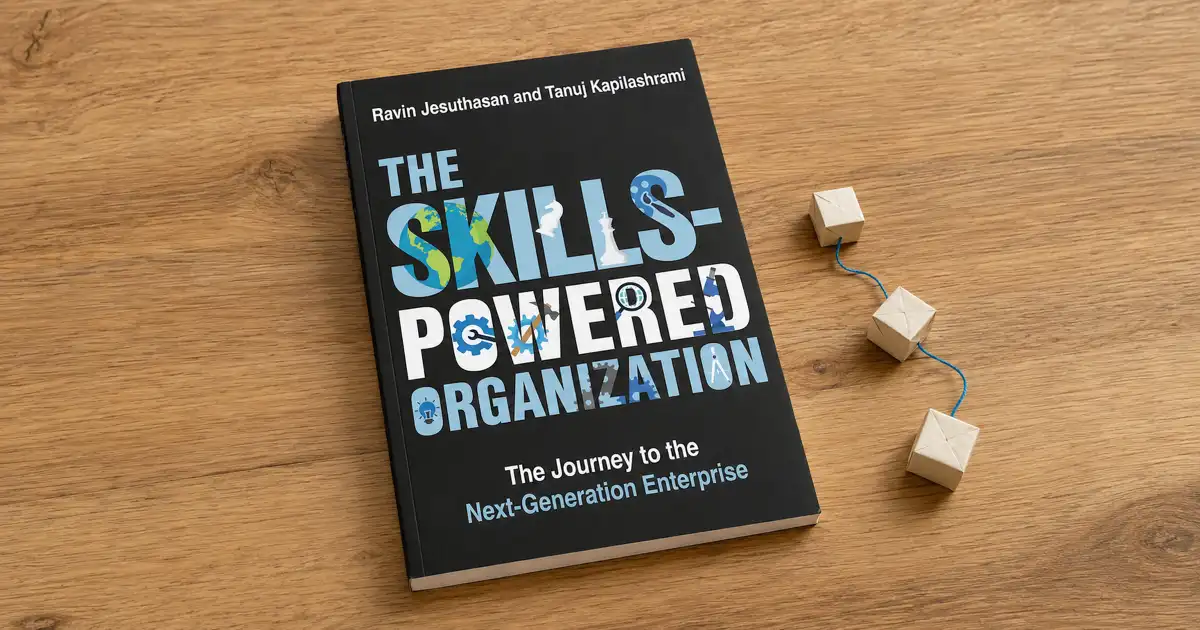 Portada de The Skills-Powered Organization sobre una mesa de madera, junto a bloques de madera conectados.